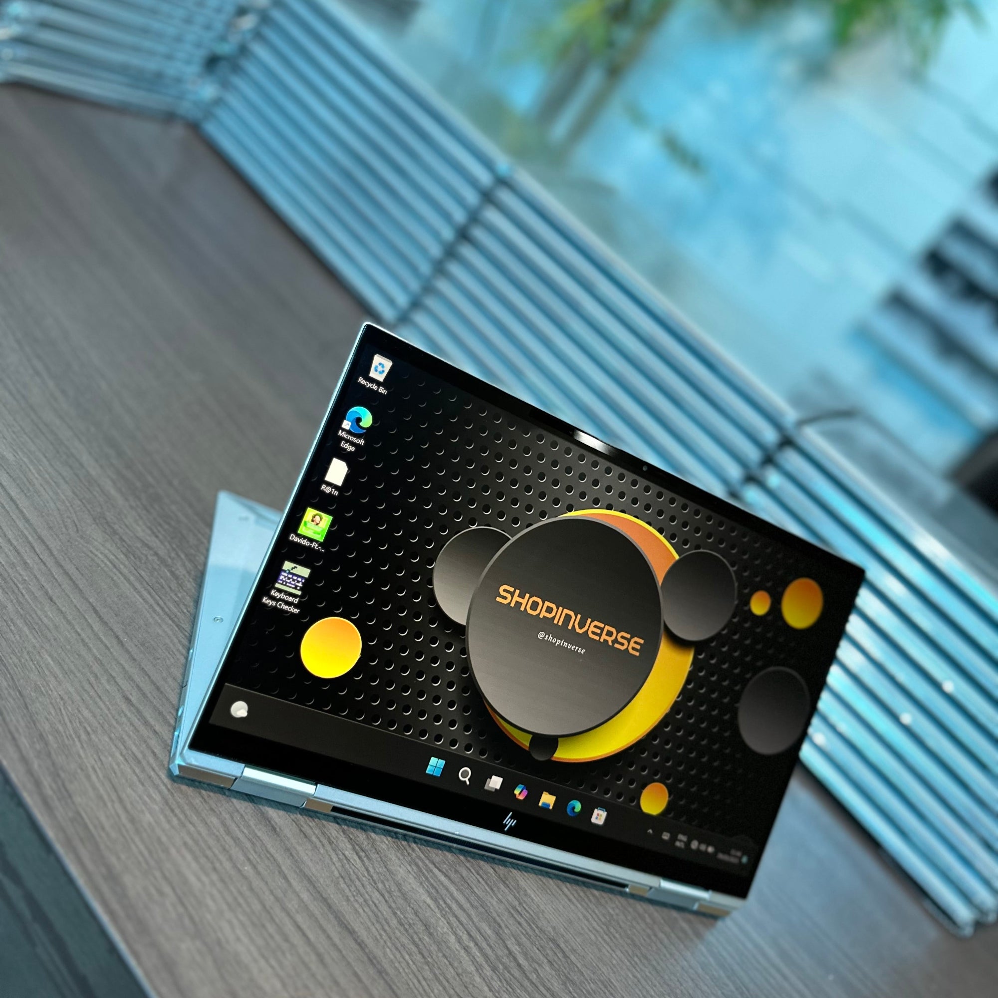 HP EliteBook x360 1030 G7 convertible laptop/tablet in silver color, featuring a touchscreen display, placed on a table.