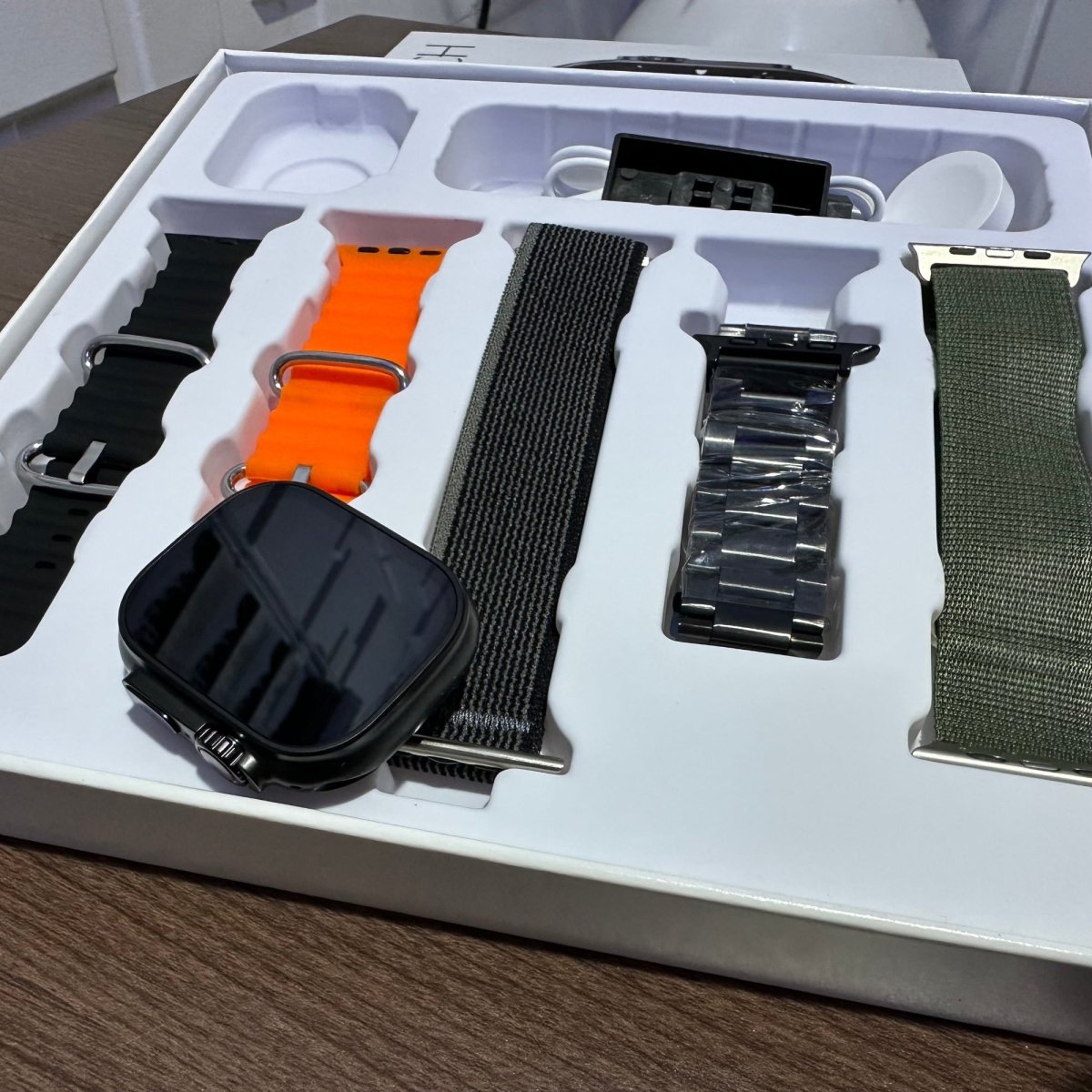 Set of smartwatch bands in a packaging box on a wooden surface