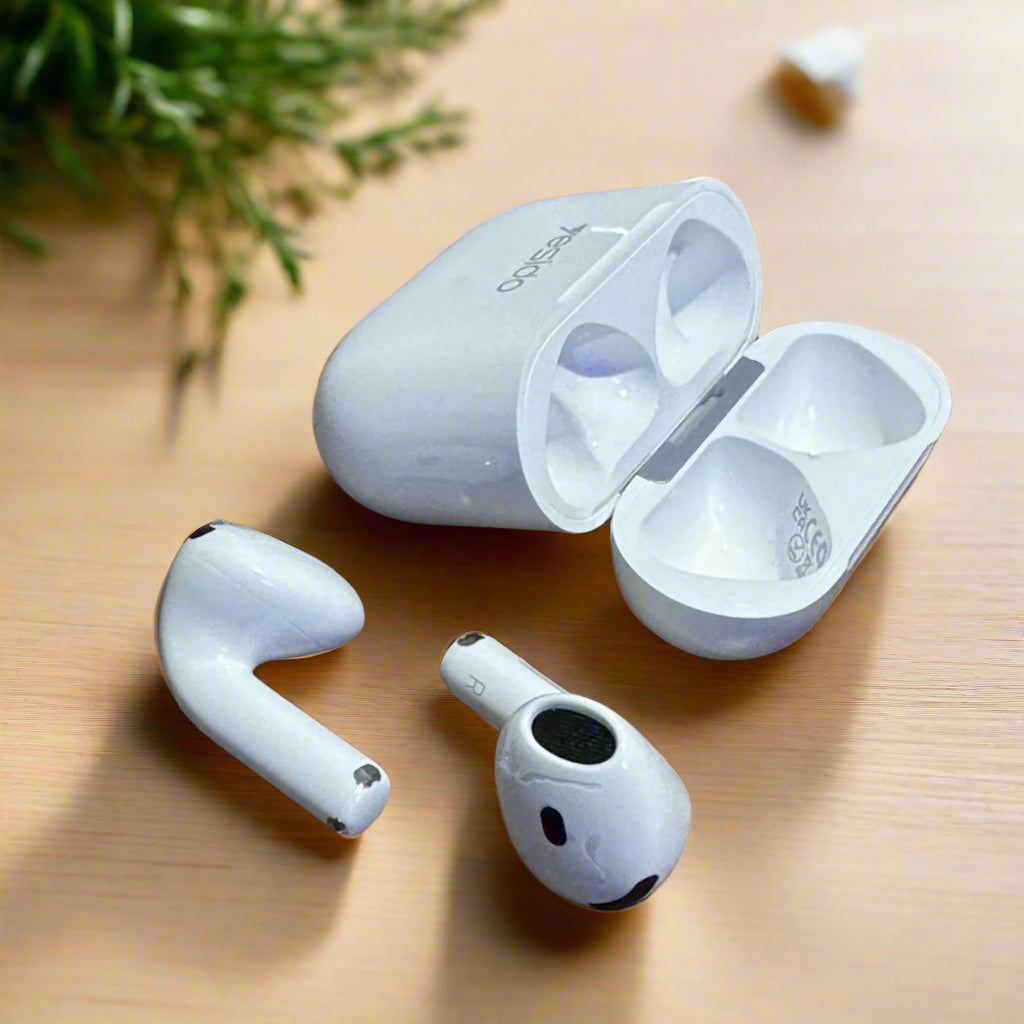 White wireless earbuds with charging case on a wooden surface