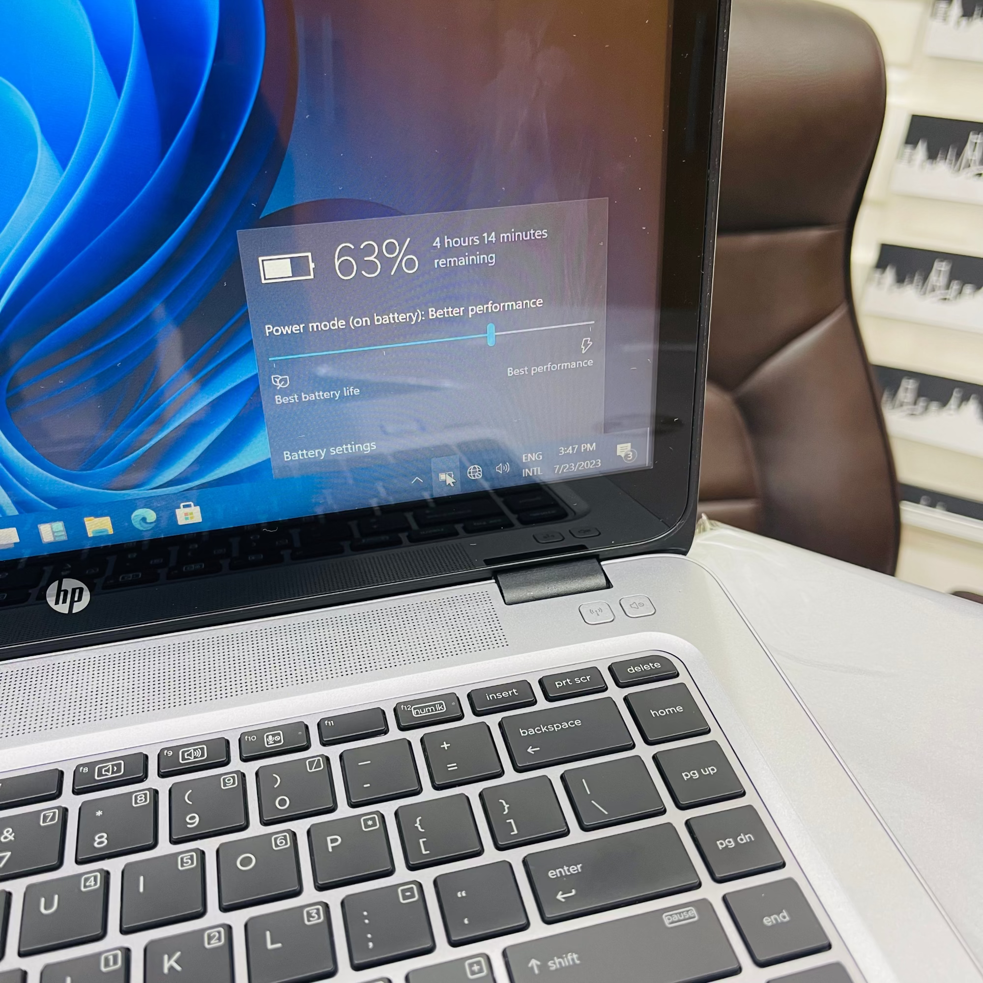 Laptop with battery status displayed on screen, placed on a surface with a blurred background.