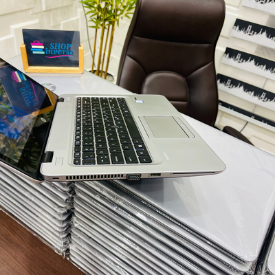 Laptop on a stack of white boxes with a chair and plant in the background