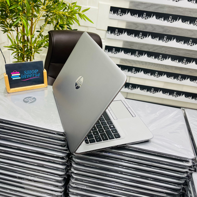 Stack of HP laptops with a plant and Shop Inverse