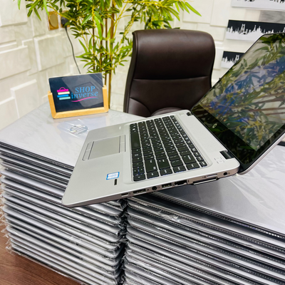 Stack of laptops on a desk with a chair and a small sign in the background